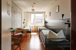明斯特Sleep Station Hostel的一间设有几张床和一张桌子及椅子的房间