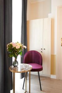 波兹南AR Apartamenty的一张紫色椅子,坐在桌子旁,花瓶