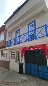 埃迪尔内5RoomsPansiyon的一座带蓝色门的建筑和一个带红色鲜花的阳台