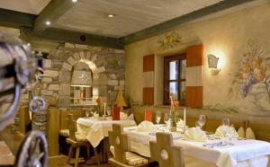 拉德施塔特罗马少年酒店的一间设有白色桌椅和石墙的餐厅