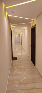 盖尼特拉Appartement à la plage Mehdia pour famille uniquement的一条带白色墙壁的走廊和一条带黄色灯光的长走廊