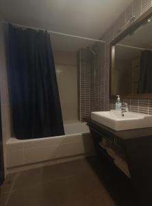 CastellfortAparthotel Castellfort的浴室配有水槽、淋浴和浴缸。