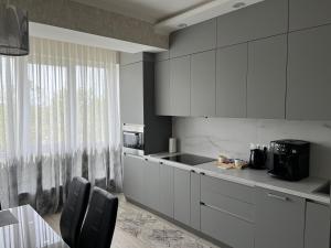 基希讷乌Dendrarium Park Apartment的厨房配有白色橱柜和桌椅