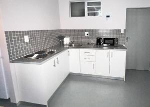 约翰内斯堡Matcha themed Apartment in City的厨房配有白色橱柜、水槽和微波炉
