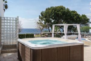 坎普德玛Alua Gran Camp de Mar的毗邻大海的庭院设有按摩浴缸。