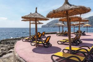 坎普德玛Alua Gran Camp de Mar的海滩上的一组椅子和遮阳伞