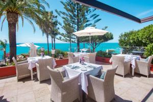 拉戈斯米兰达别墅精品酒店的餐厅设有桌椅,以大海为背景
