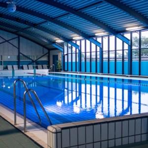 比伦Vakantiepark Klein Vaarwater的大型室内游泳池拥有蓝色的墙壁和窗户