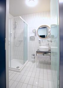 慕尼黑Das Schreder Hotel的带淋浴、盥洗盆和镜子的浴室
