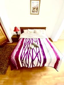 萨洛RoNi RoOms的卧室内的一张带紫色和白色棉被的床