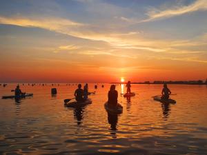 圣特马坦迪克Bed & Brasserie Het Kosthuys的一群人坐在水上的皮划艇上,日落时分