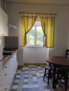 新普罗恩萨Casa Xara的厨房配有桌子和带黄色窗帘的窗户