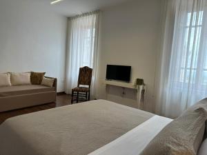 瓜尔多卡塔内奥RESIDENCE IL GROTTINO的一间卧室配有一张床、一张沙发和一台电视。