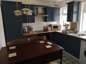 贝尔法斯特Cosy Town House的厨房配有深蓝色橱柜和木桌