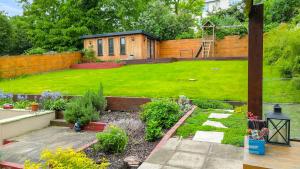 伦敦Cosy Luxurious Family Home的一个带草坪的花园和带围栏的房子