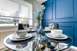 克罗伊登Contemporary 4 bedroom detached house with parking and city links的蓝色的用餐室配有玻璃桌和椅子