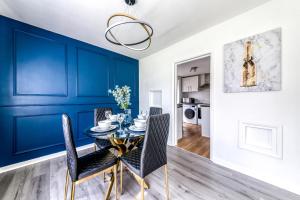 克罗伊登Contemporary 4 bedroom detached house with parking and city links的一间拥有蓝色墙壁和桌椅的用餐室