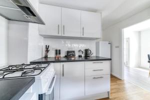 克罗伊登Contemporary 4 bedroom detached house with parking and city links的白色的厨房配有白色橱柜和炉灶。