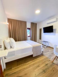 普雷亚Aiolos Hotel & Discoveries的卧室配有一张白色大床和电视。