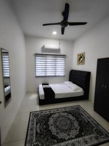 淡马鲁Homestay Temerloh Near Hospital with Private Pool Wi-Fi Netflix的一间卧室配有一张带吊扇和地毯的床。