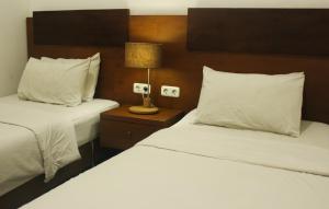 日惹格拉哈吉纳斯赫科塔巴鲁酒店的酒店客房设有两张床和床头灯。