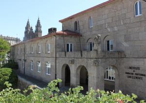 圣地亚哥－德孔波斯特拉San Clemente by Pousadas de Compostela的一座古老的石头建筑,后面有钟楼