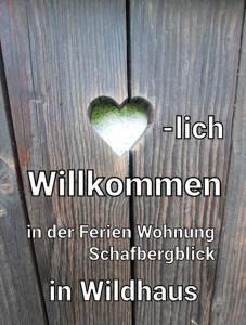 维尔德豪斯Ferienwohnung Schafbergblick的木桌上的心,上面写着羽毛中高柳岛血症的字眼