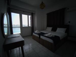 希俄斯Omiros rooms的一间卧室设有两张床、一张桌子和一个窗口。