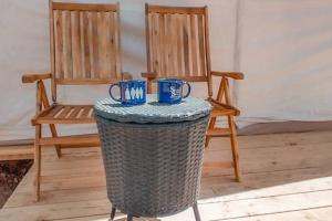 汤姆斯通Silver Spur Homestead Luxury Glamping -The Tombstone的两张椅子和一张桌子,上面有两个蓝色的杯子
