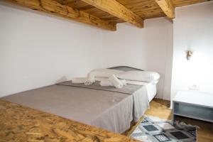 LakkíonMike's Guesthouse的白色客房的一张床位,设有木制天花板