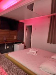 阿瓜斯克拉腊斯Hotel 1001 Prime Ade Águas Claras的卧室配有白色床和粉红色照明