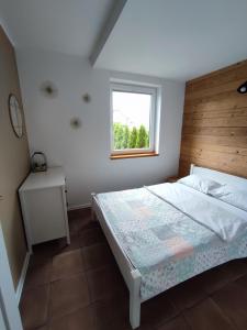 米科瓦伊基SOWI KĄT domki i apartamenty的一间卧室配有一张带木制床头板的床和窗户。