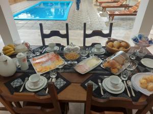 伊利亚孔普里达Pousada Ninhal das Garças的一张带早餐食品的桌子和一个游泳池