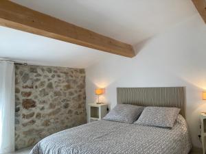 格吕桑Gîte de 12 personnes au cœur d'un domaine viticole的一间卧室设有一张床和石墙