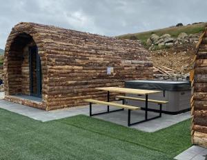 BannvaleGreenview Glamping Pods的石头建筑,设有两张野餐桌和一个浴缸