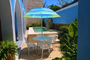 梅里达Boutique Casa Azuli Santiago的庭院内桌椅和遮阳伞