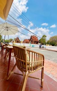 琅勃拉邦Barn Laos Luangprabang Hostel的一张带桌子和雨伞的木凳