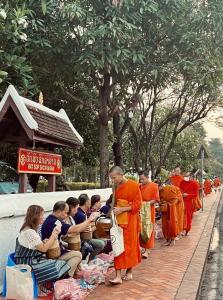 琅勃拉邦Barn Laos Luangprabang Hostel的一群身着橙色长袍的僧侣站在一排队伍中