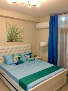 宿务Condo Near Mactan Airport的一间卧室配有一张带蓝色和绿色枕头的床