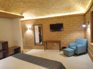 莱瓦镇La Alhambra Hotel Boutique的卧室配有1张床和1台砖墙电视