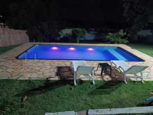 伊比乌纳Piscina Climatizada - Chácara em Condominio的一组椅子和一个晚上的游泳池