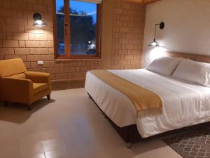 莱瓦镇La Alhambra Hotel Boutique的卧室配有床、椅子和窗户。