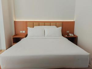 泗水AYMAN SYARIAH HOTEL的一张配有白色床单和枕头的大床
