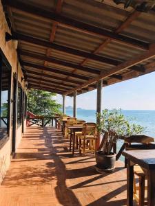达叻府Rock sand Resort的一个带桌椅的木制门廊和大海