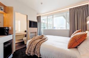 陶朗加CitySide Hotel Tauranga的酒店客房设有一张床和一个大窗户