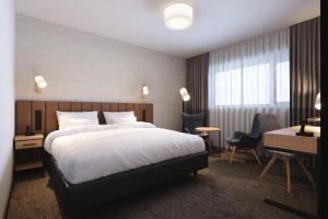 华沙Four Points by Sheraton Warsaw Mokotow的酒店客房设有一张大床和一张书桌。