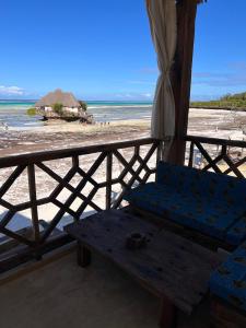 米查维The View of Zanzibar的海滩上的长凳,带遮阳伞和大海