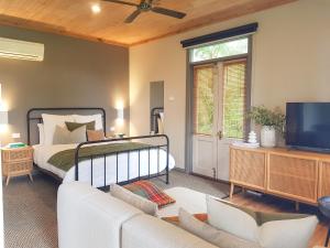 仙女港克伦马拉乡村别墅及山林小屋的一间卧室配有一张床、一张沙发和一台电视。
