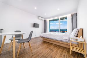 襄阳郡Sky Sea Pension的一间卧室配有一张床、一张桌子和一个窗户。