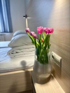 利沃夫凯梅勒别墅旅馆的卧室桌子上的粉红色郁金香花瓶